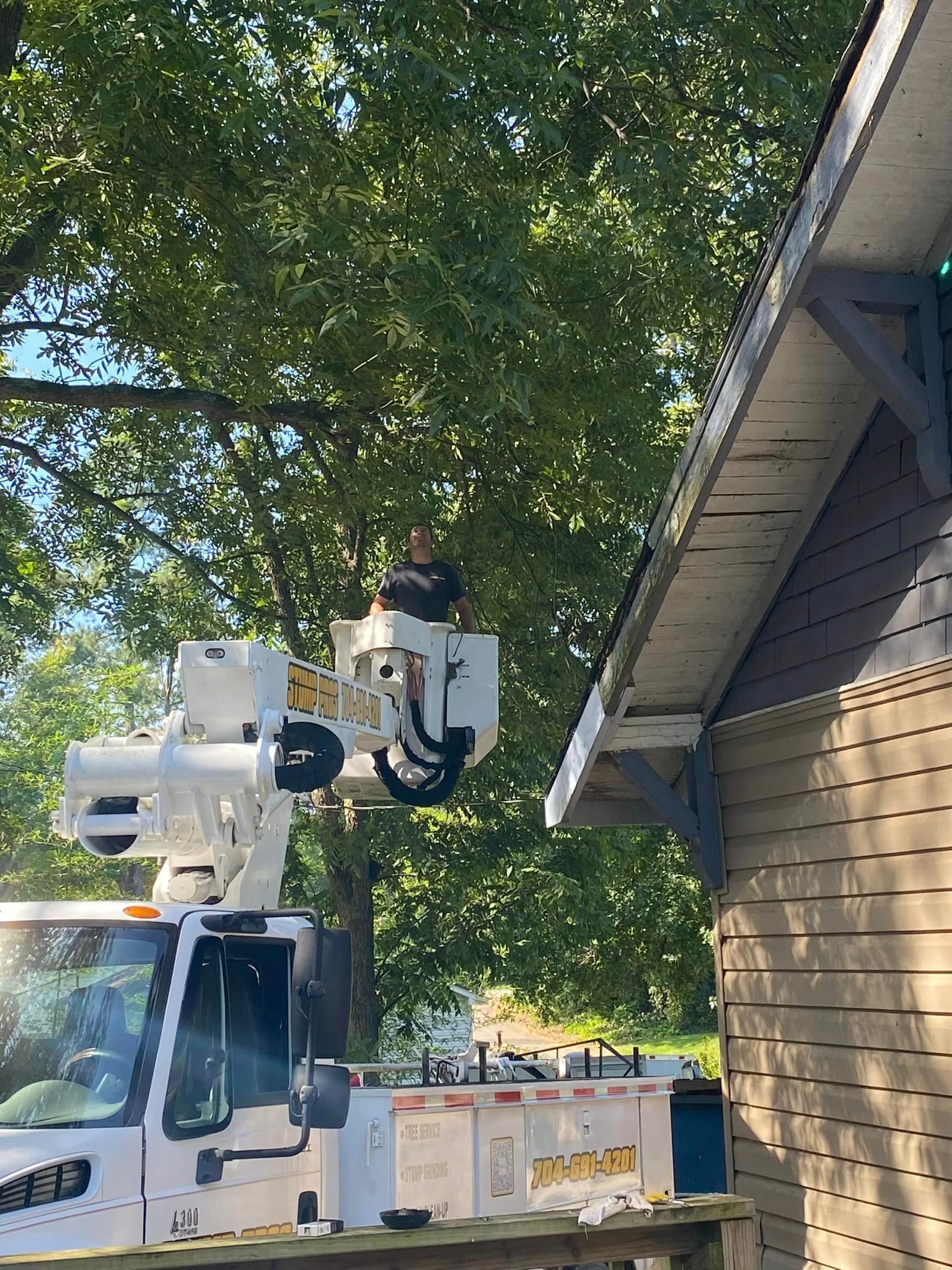 A man is working on the roof of a house with a crane.