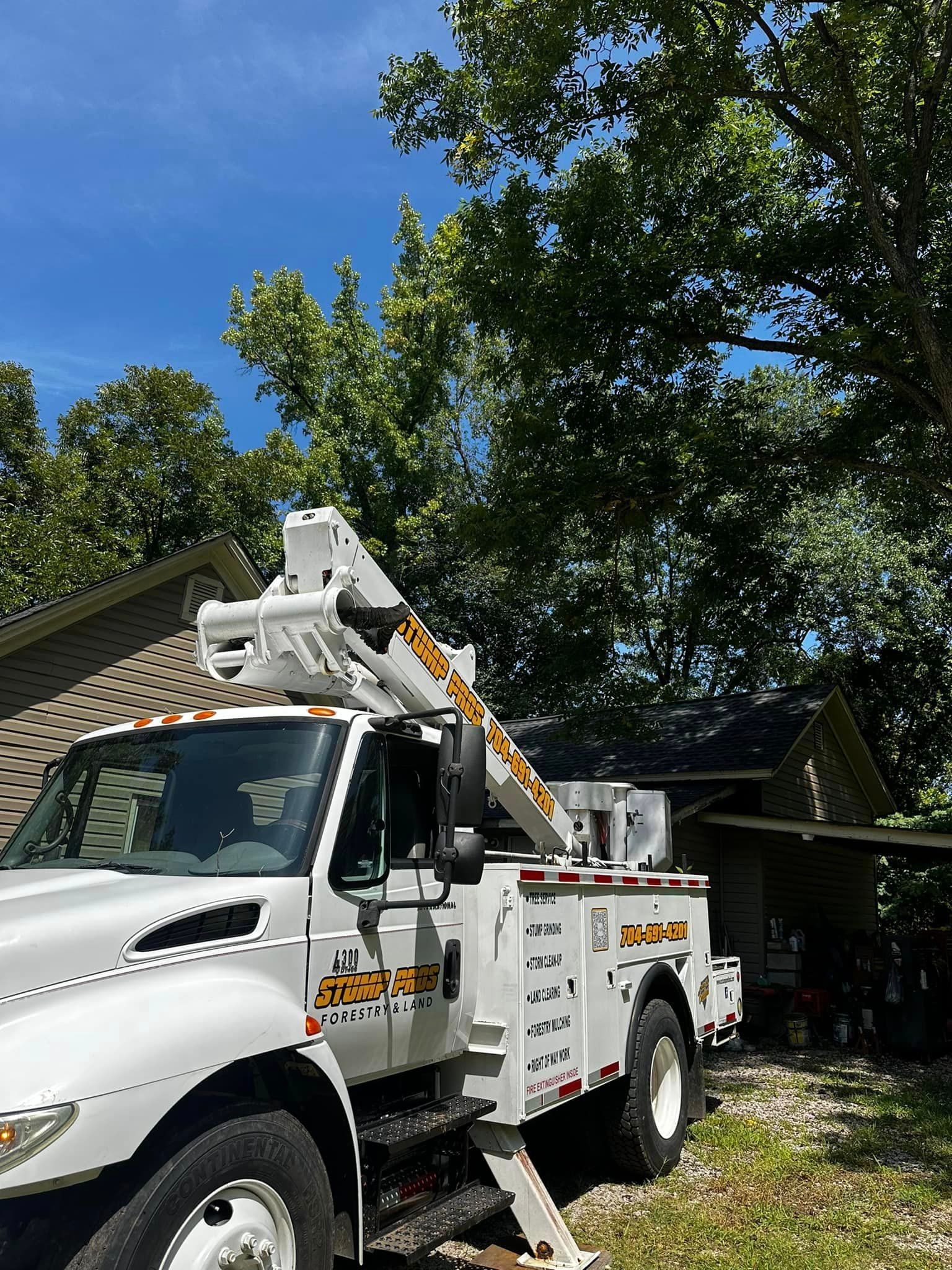 A white truck with a crane on top of it is parked in front of a house.