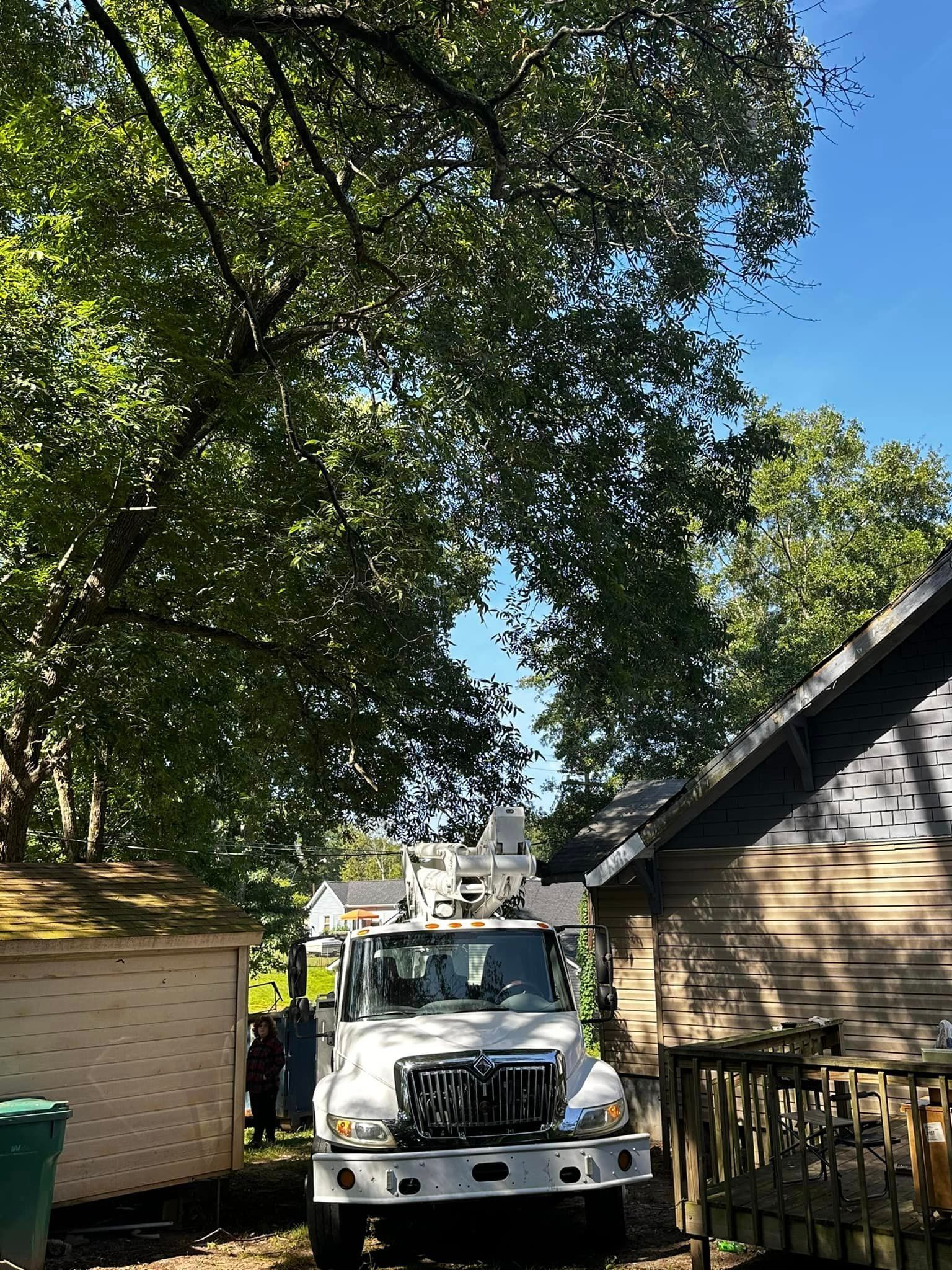 A white truck with a crane on top of it is parked in front of a house.