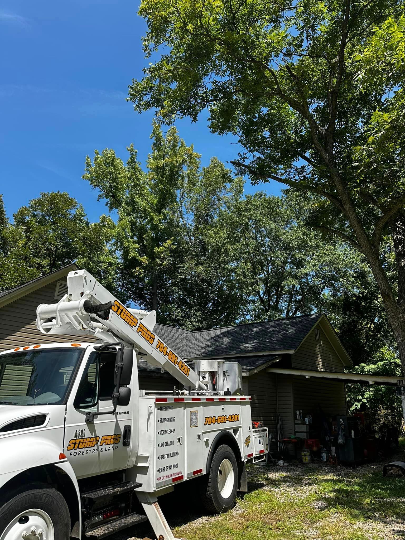 A white truck with a crane on top of it is parked in front of a house.