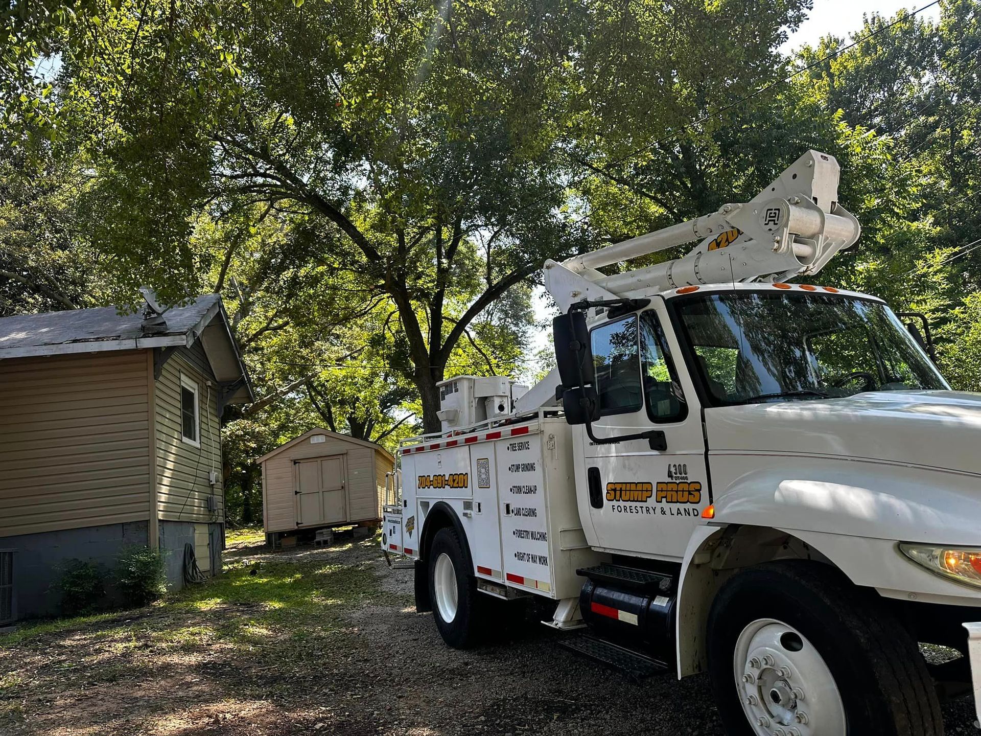 A white truck with a crane on top of it is parked in front of a house.