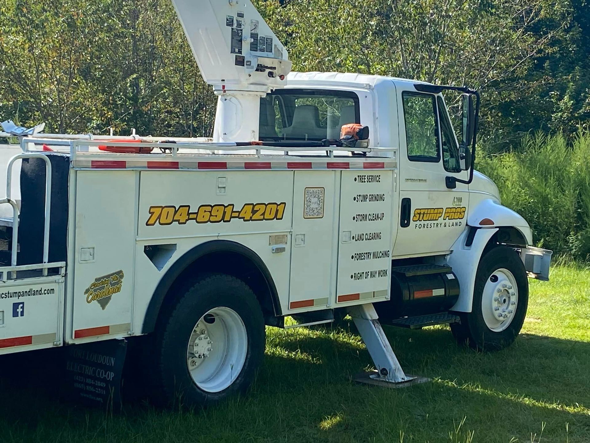 A white tow truck is parked in a grassy field