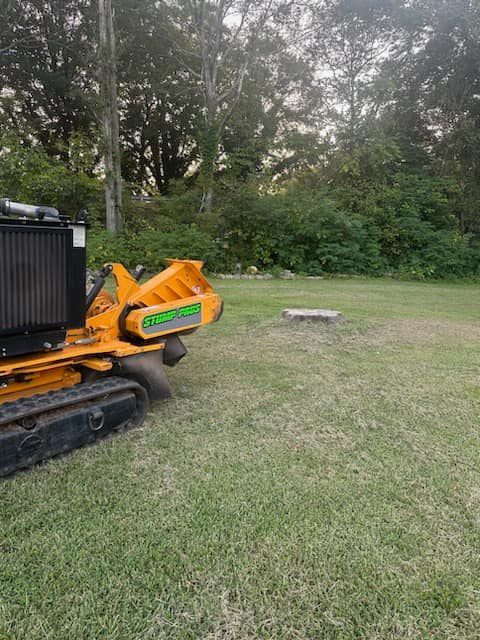 A stump grinder is sitting on top of a lush green field.