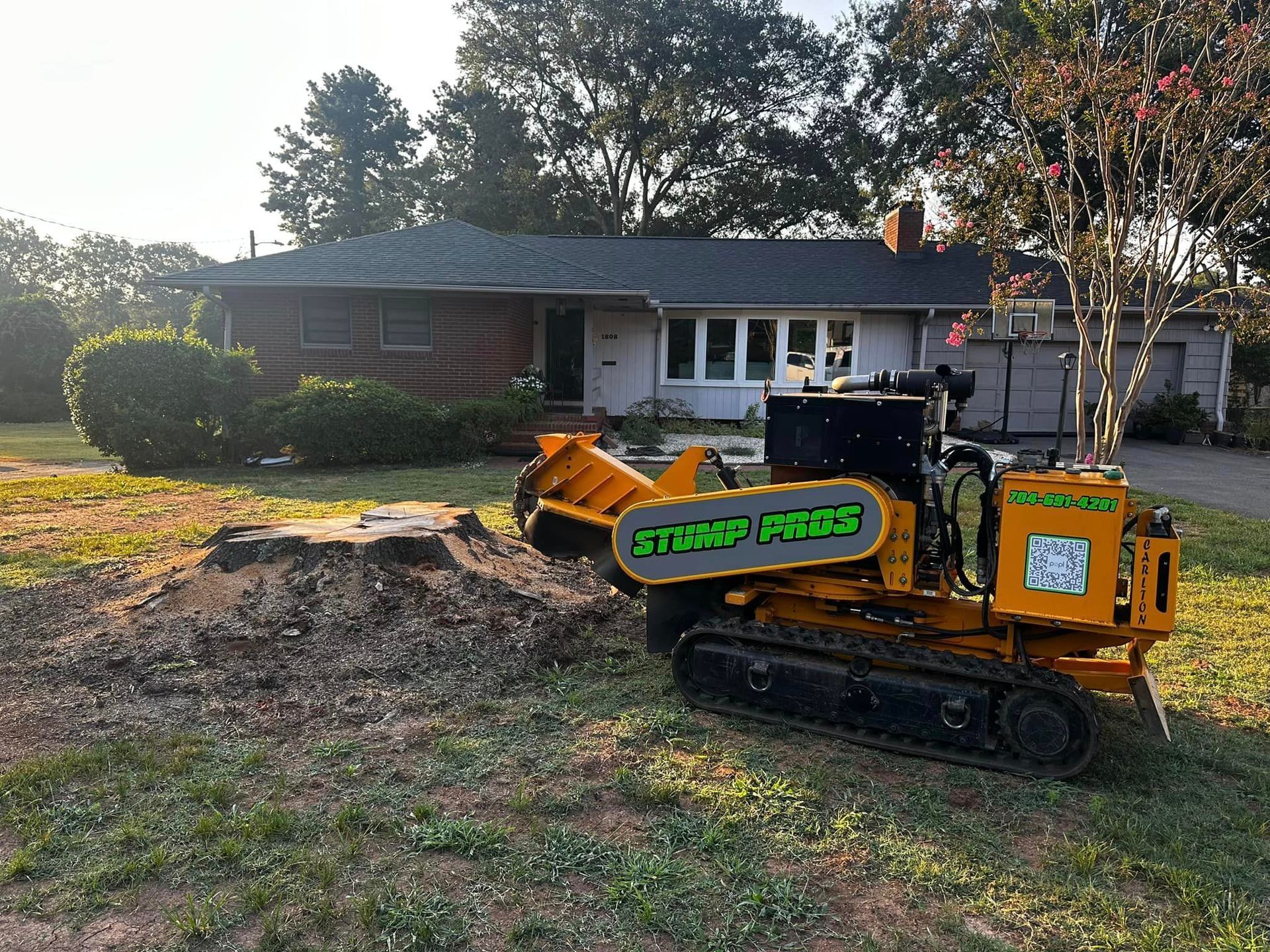 A stump grinder is sitting in front of a house.