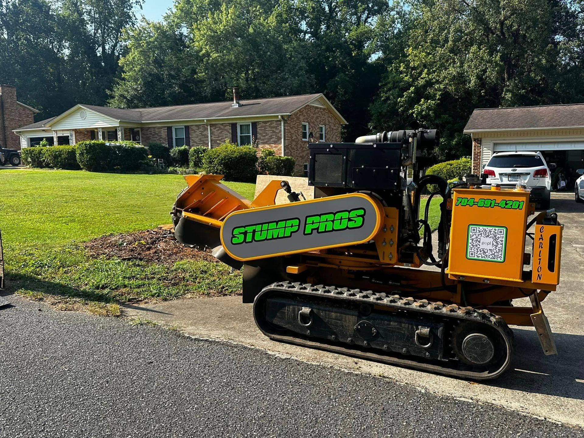 A yellow tractor is parked on the side of the road in front of a house.