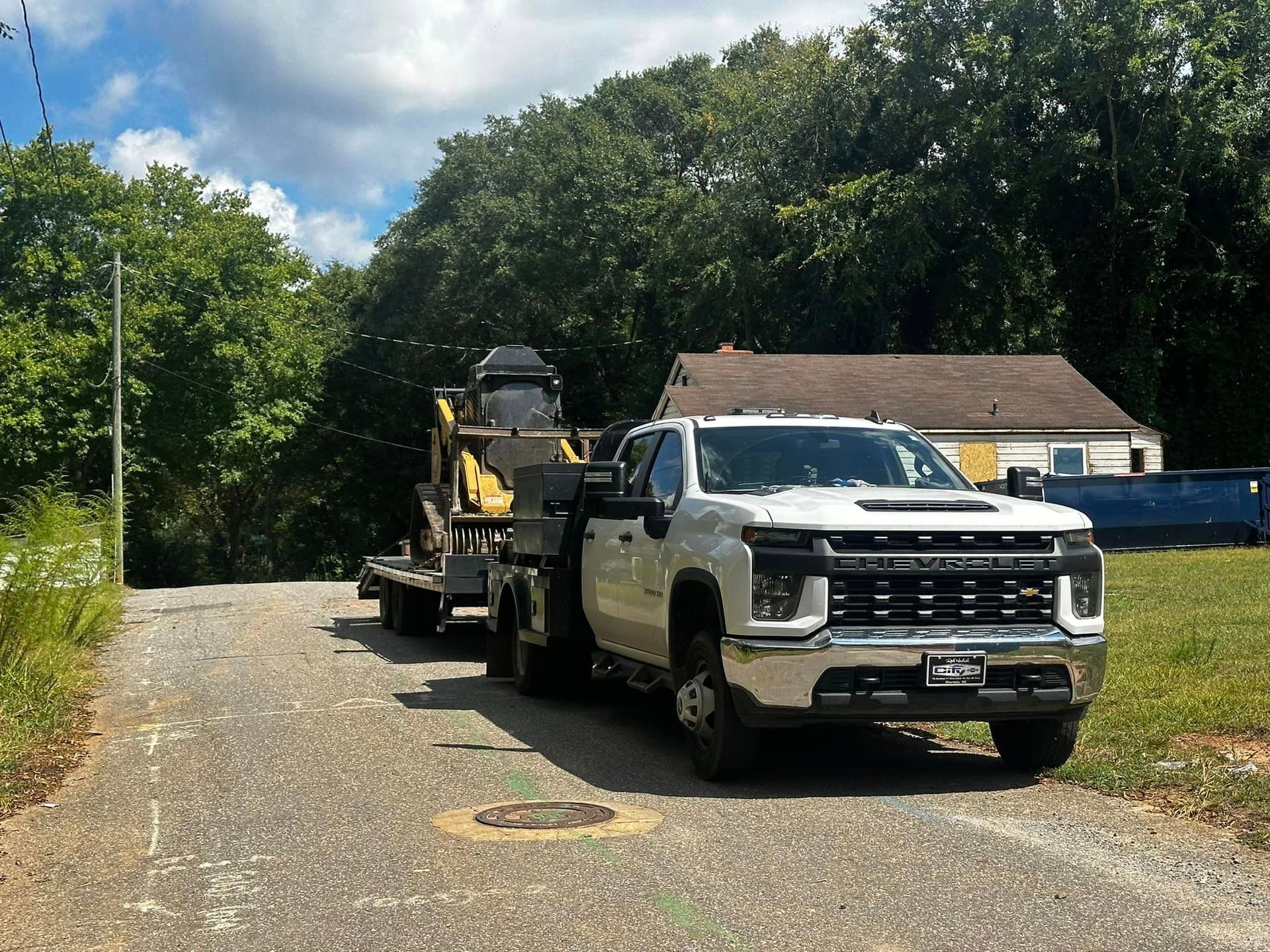 A white truck is parked on the side of the road with a trailer attached to it.