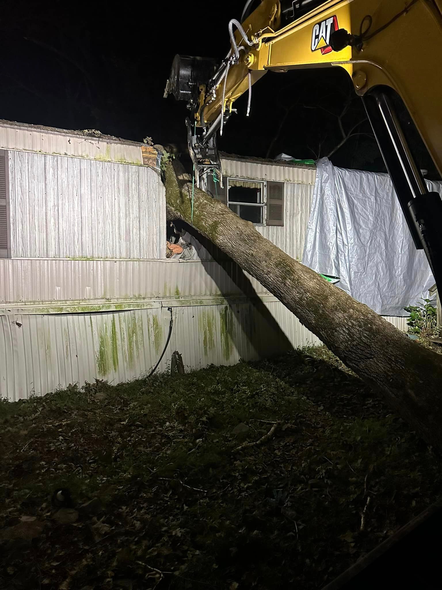 A large tree is fallen on top of a mobile home.