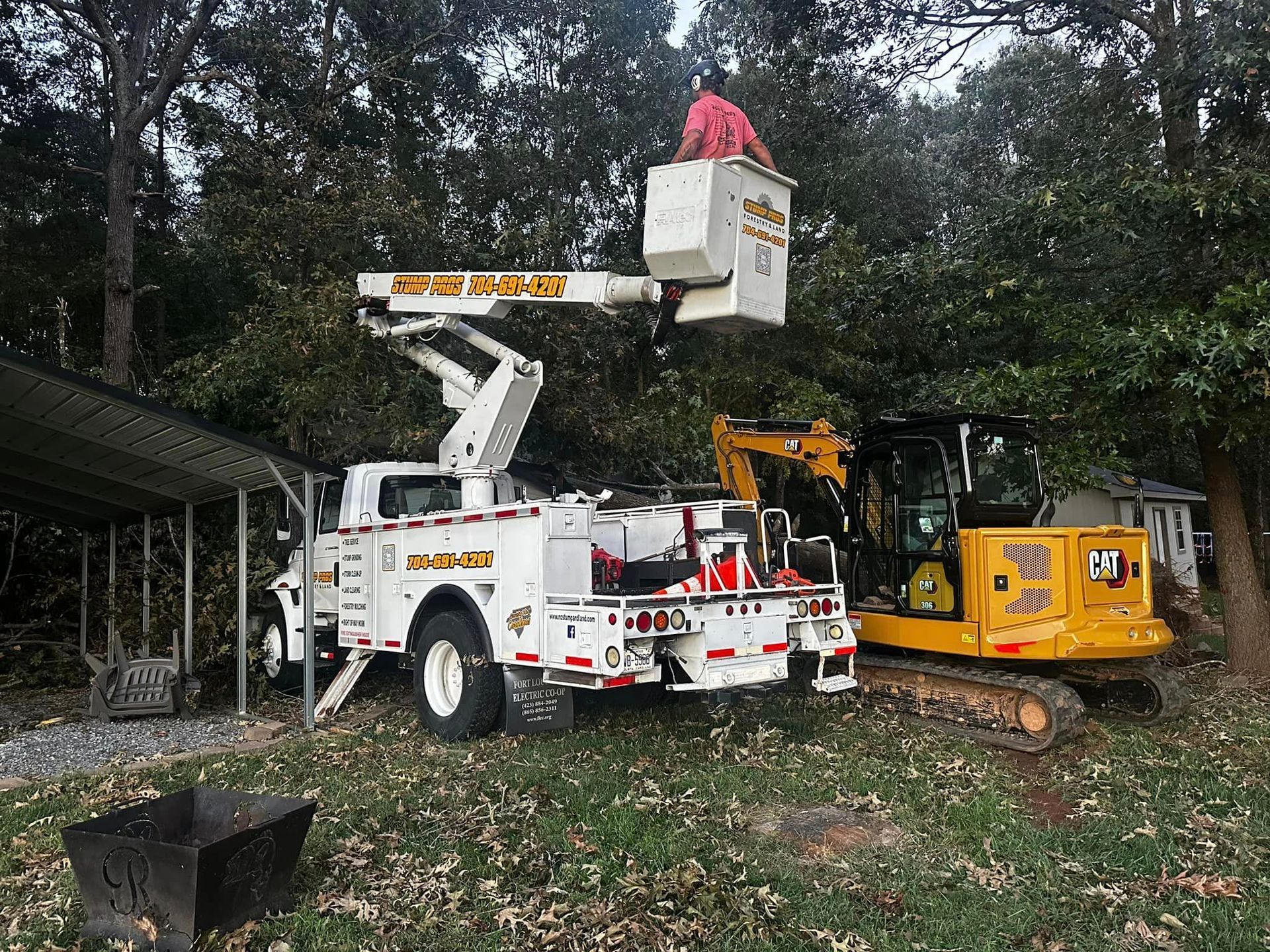 A white truck with a bucket on top of it is parked next to a yellow excavator.