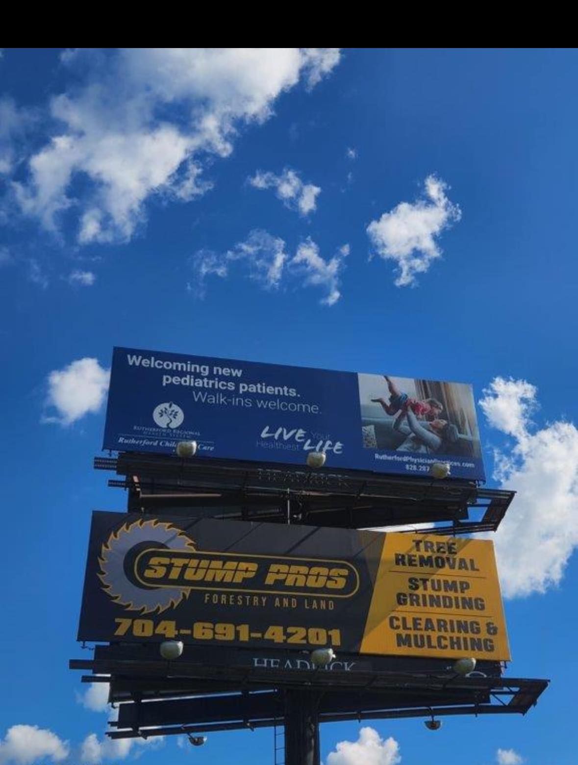 A billboard for stump pros is against a blue sky
