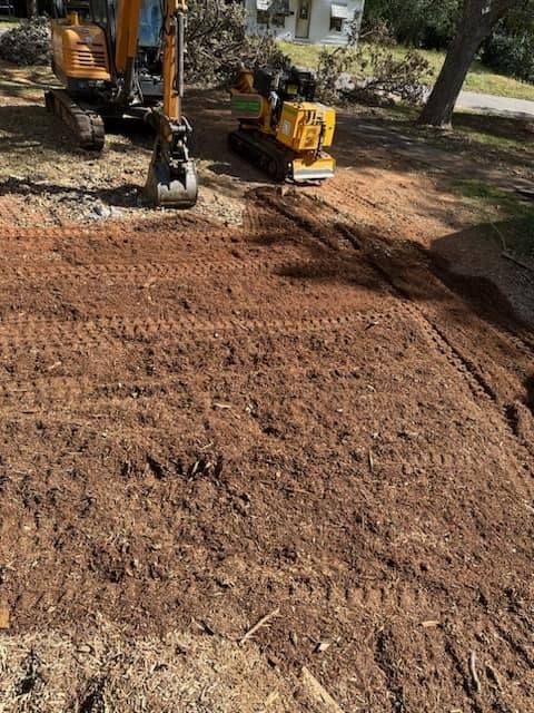 A yellow excavator is working on a dirt road.