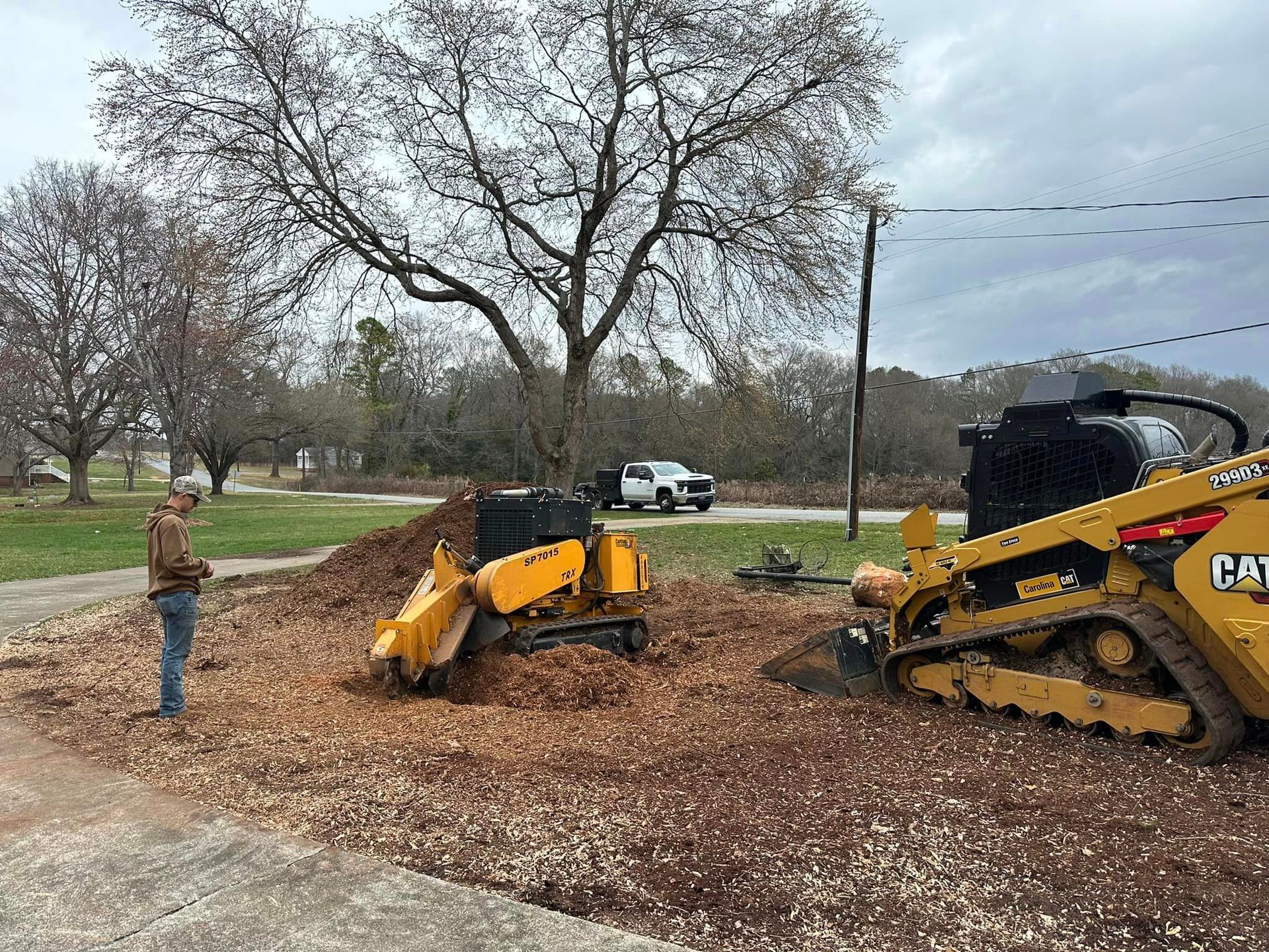 A man is standing next to a stump grinder.