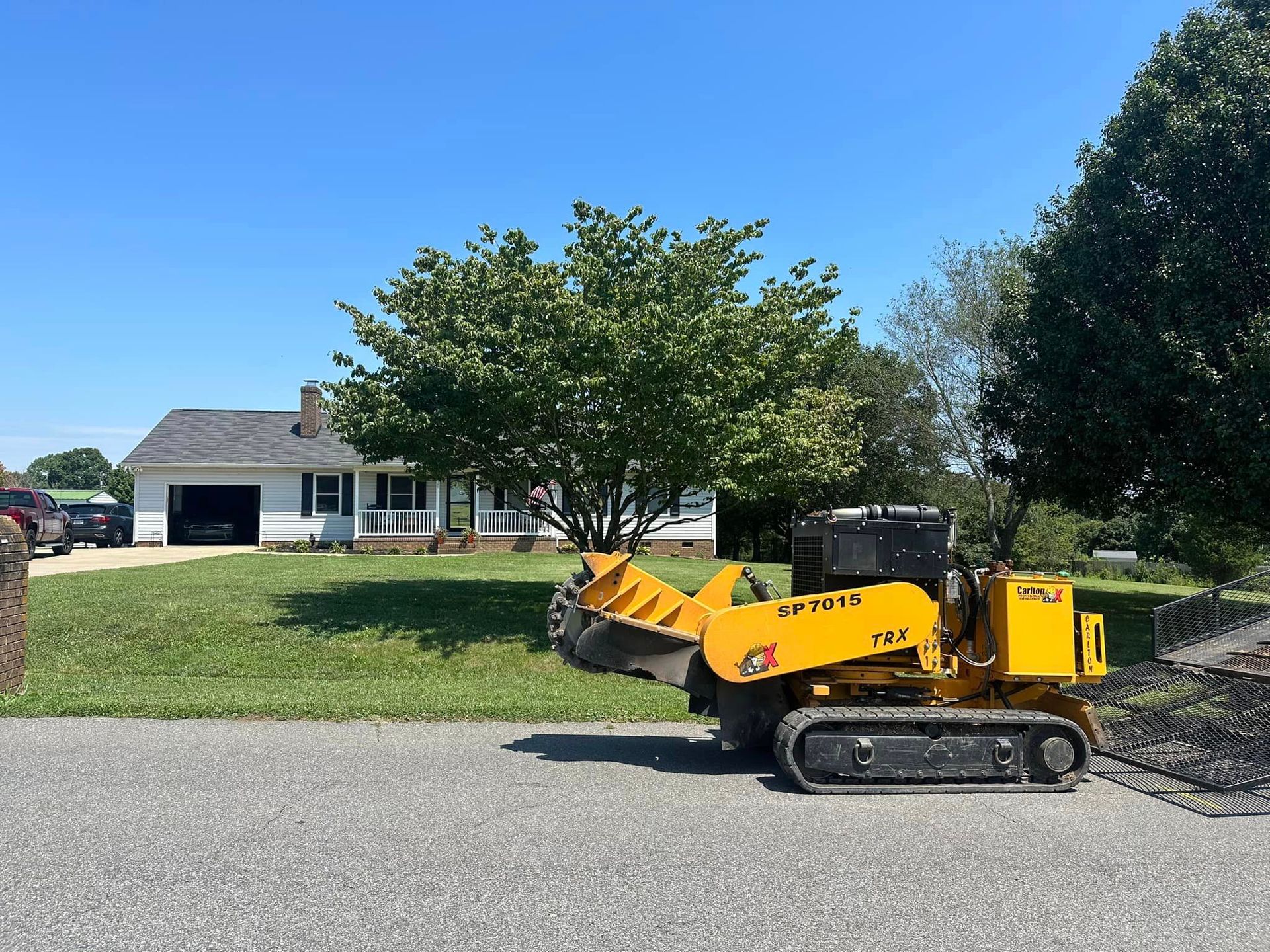 A yellow bulldozer is parked in front of a house.