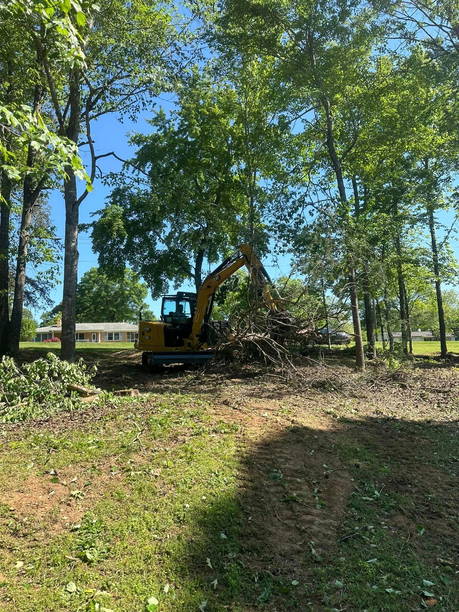 A bulldozer is cutting down trees in a yard.