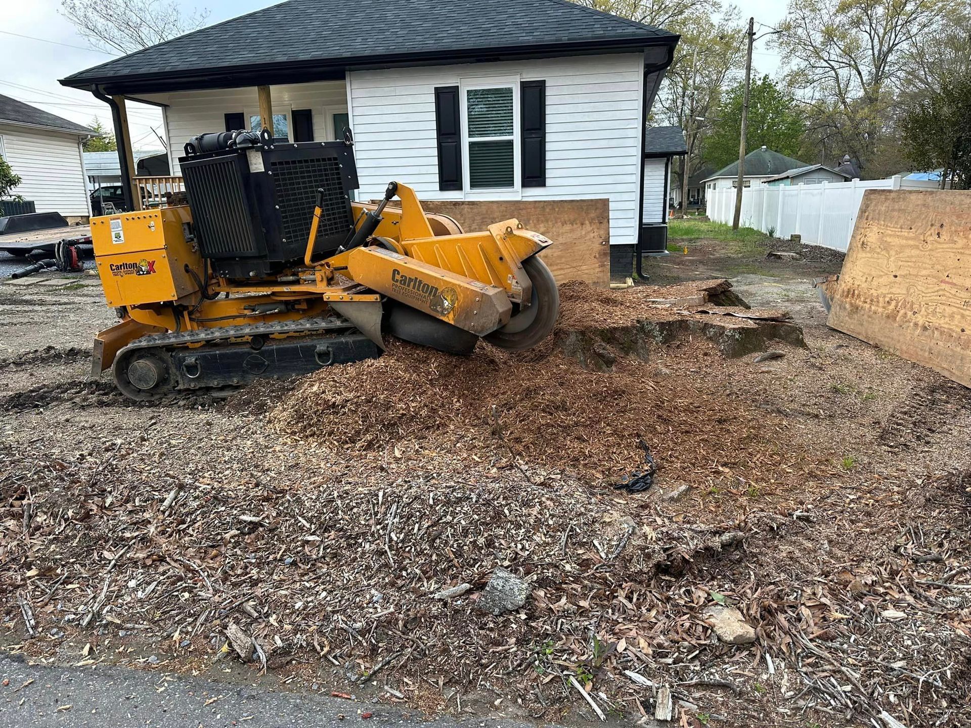 A stump grinder is sitting in front of a house.