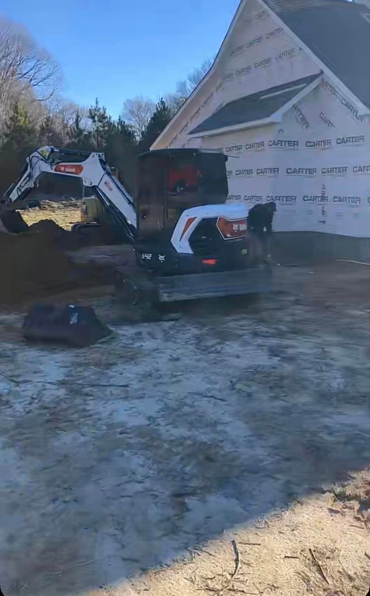 A bulldozer is moving dirt in front of a house under construction.