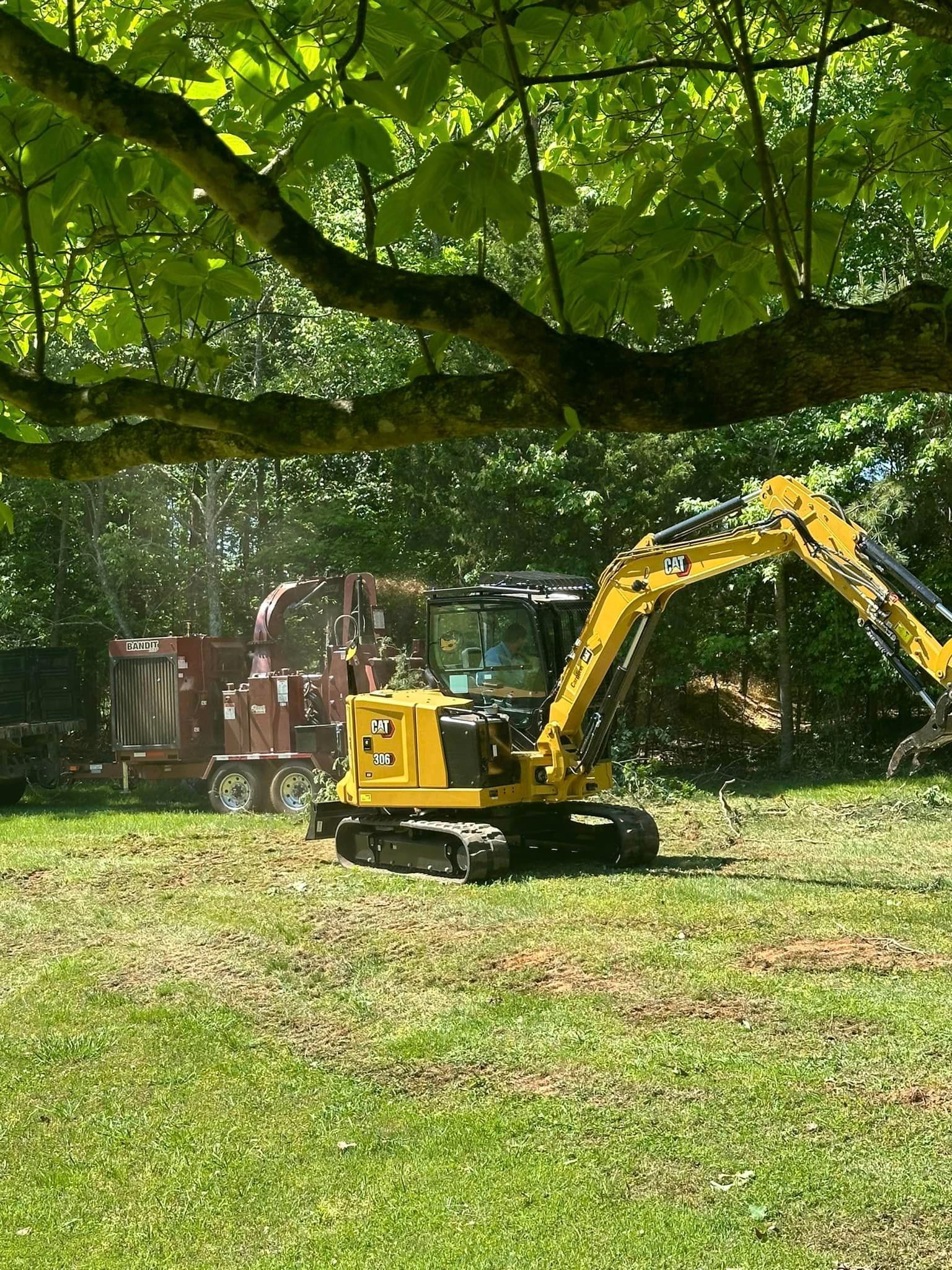 A yellow excavator is sitting on top of a lush green field.