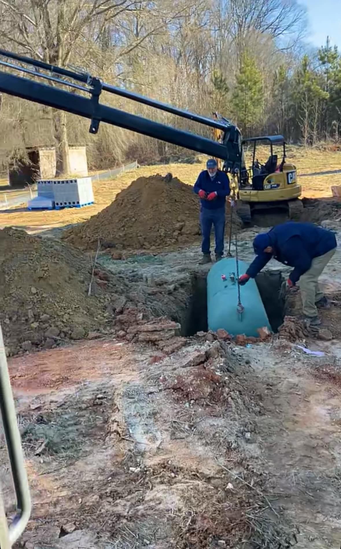 A man is digging a hole in the ground to install a septic tank.