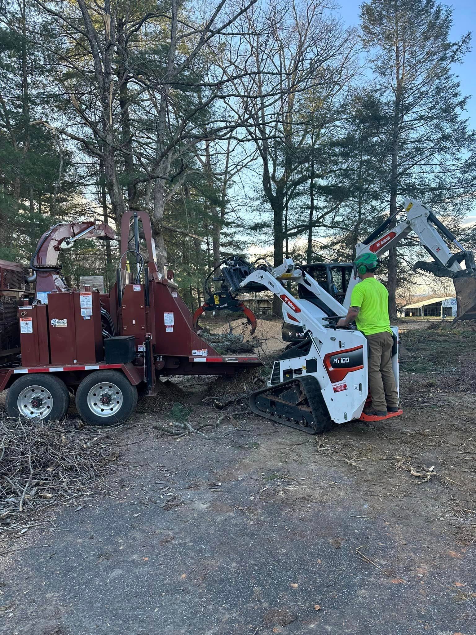 A man is standing next to a tree chipper in a parking lot.