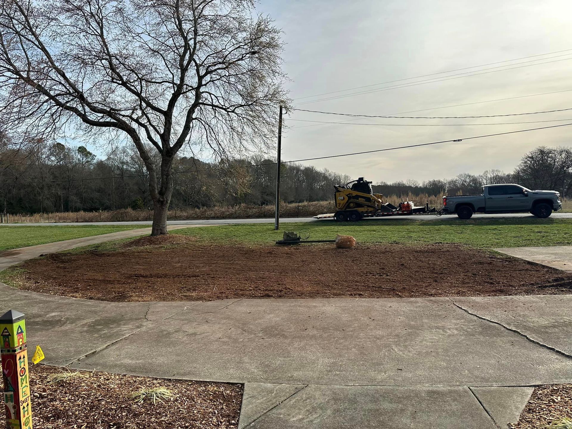A truck is driving down a road next to a tree.