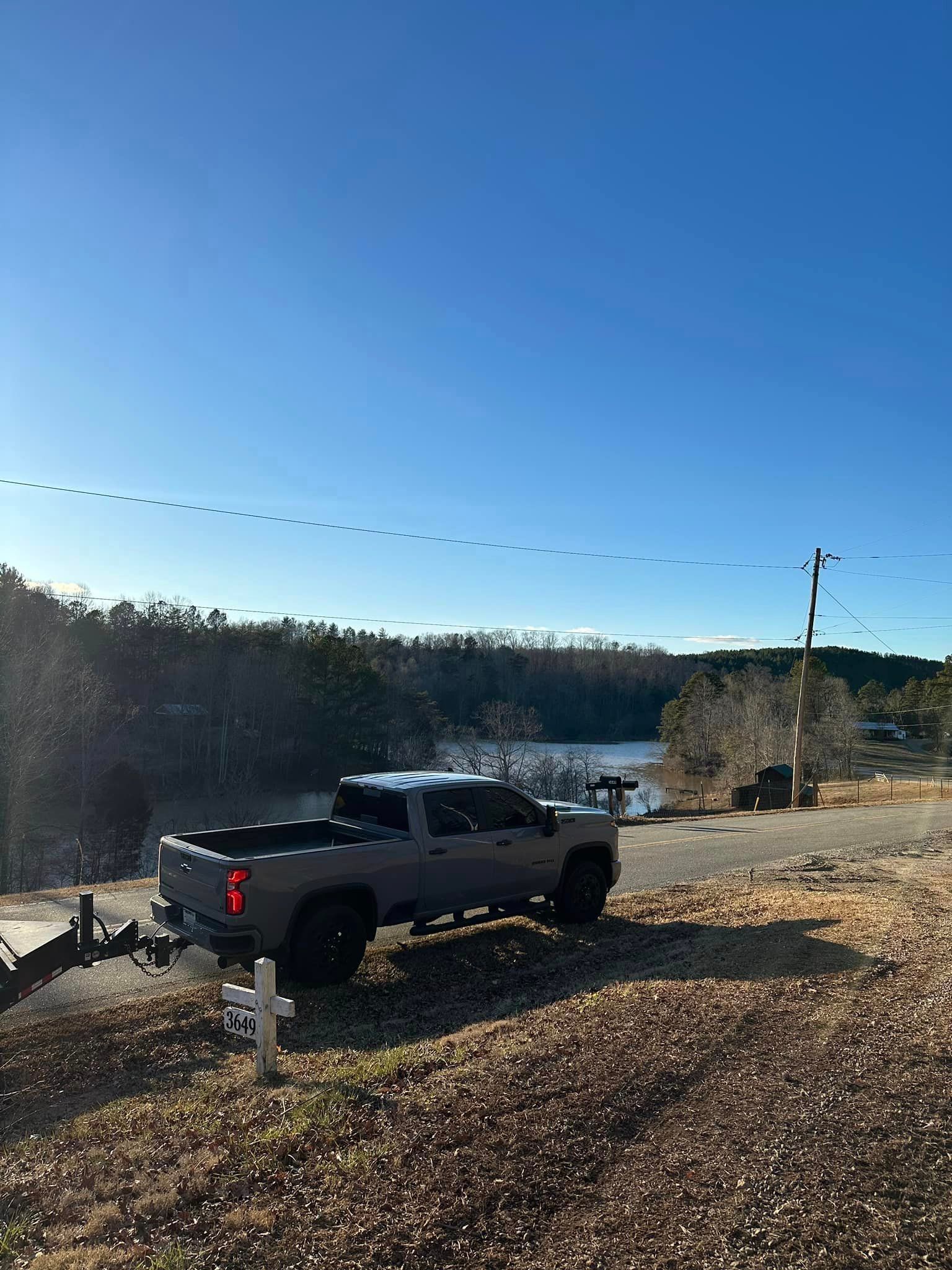 A truck is parked on the side of a road next to a lake.