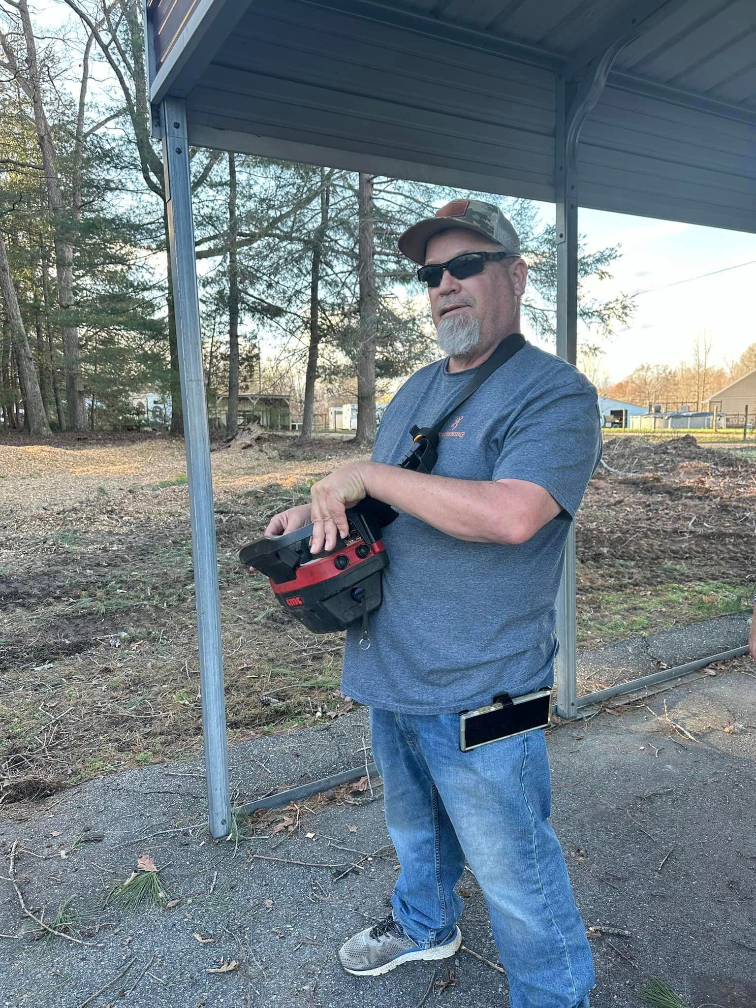 A man is standing under a covered area holding a helmet.