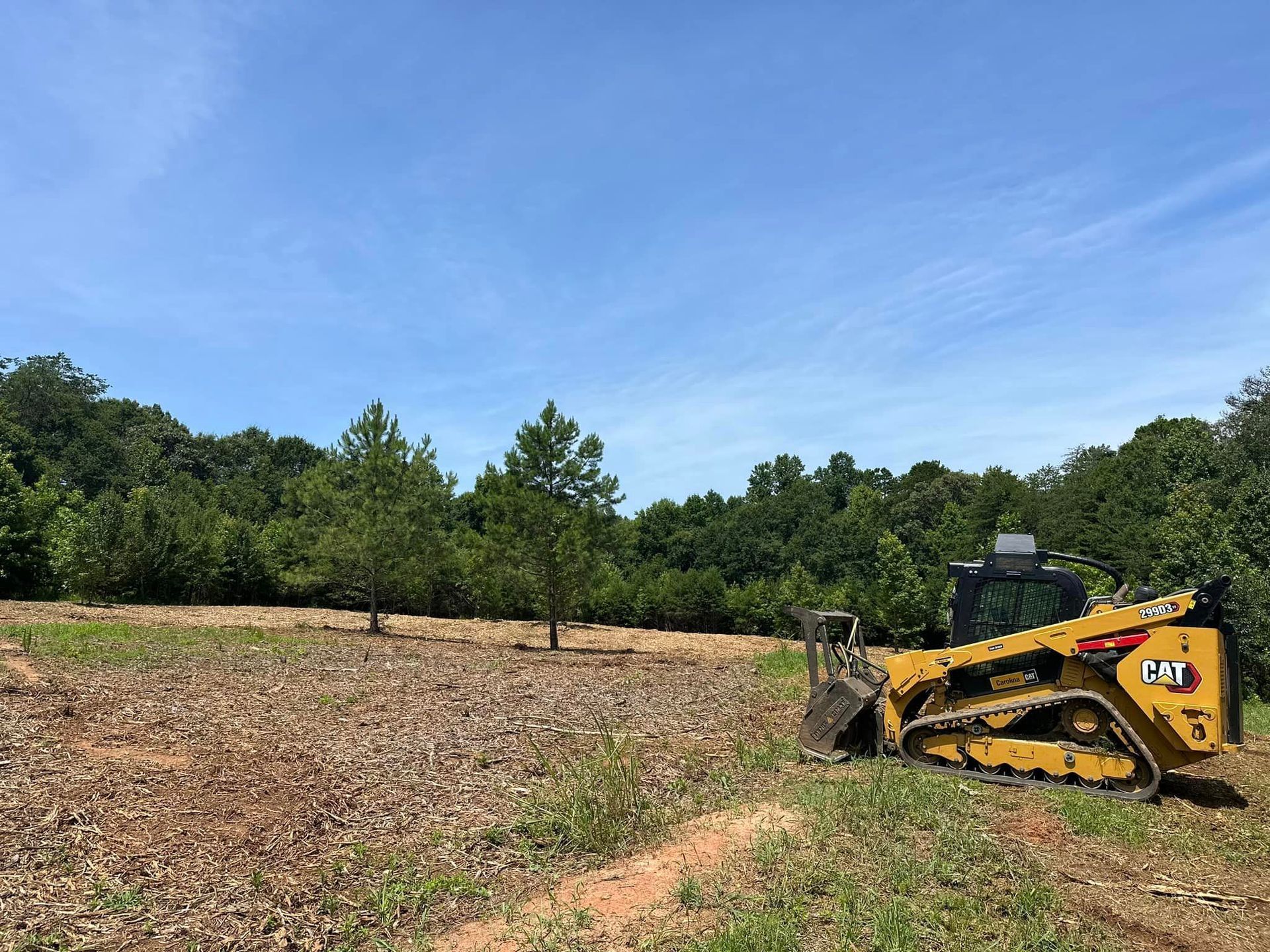 A bulldozer is parked in a field with trees in the background.