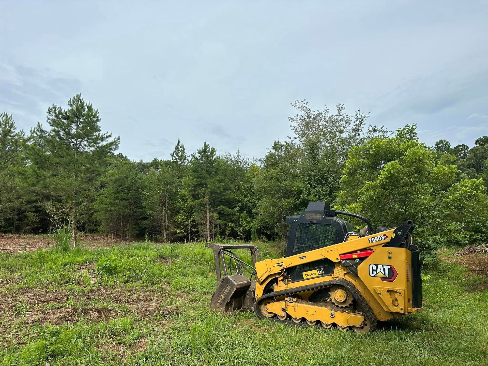A yellow bulldozer is parked in a grassy field.