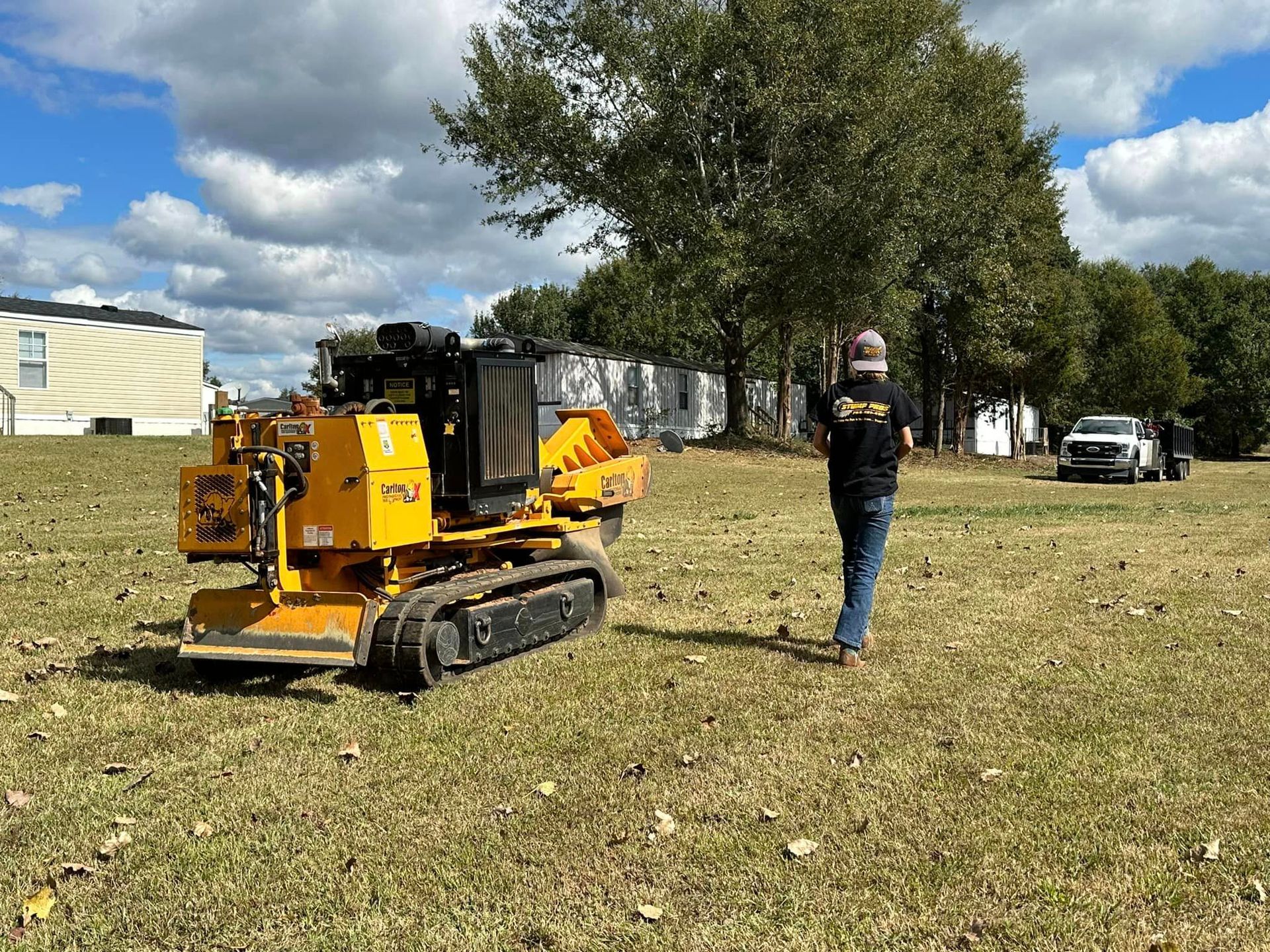 A man is standing next to a yellow machine in a field.