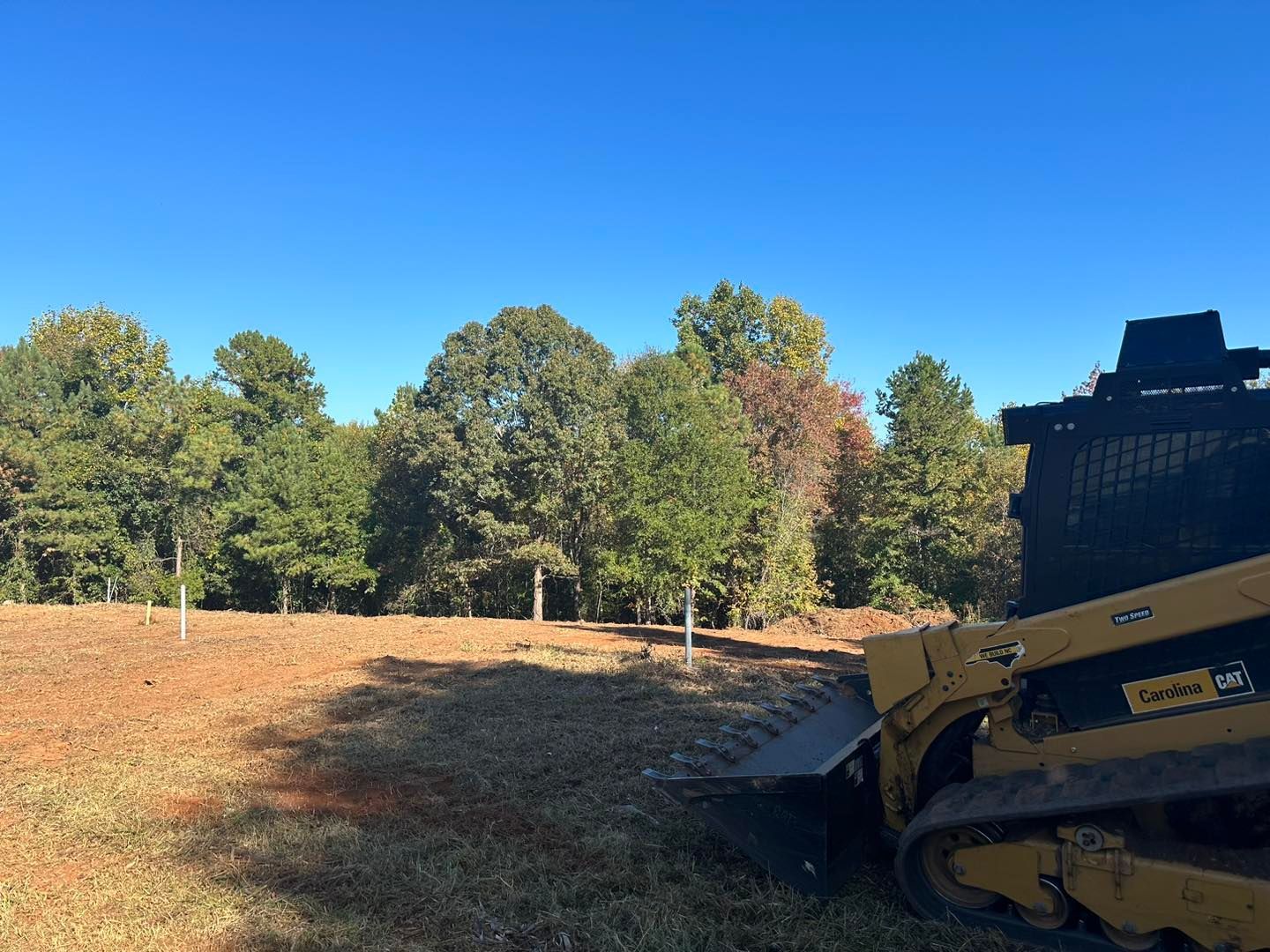 A bulldozer is sitting in a field with trees in the background.