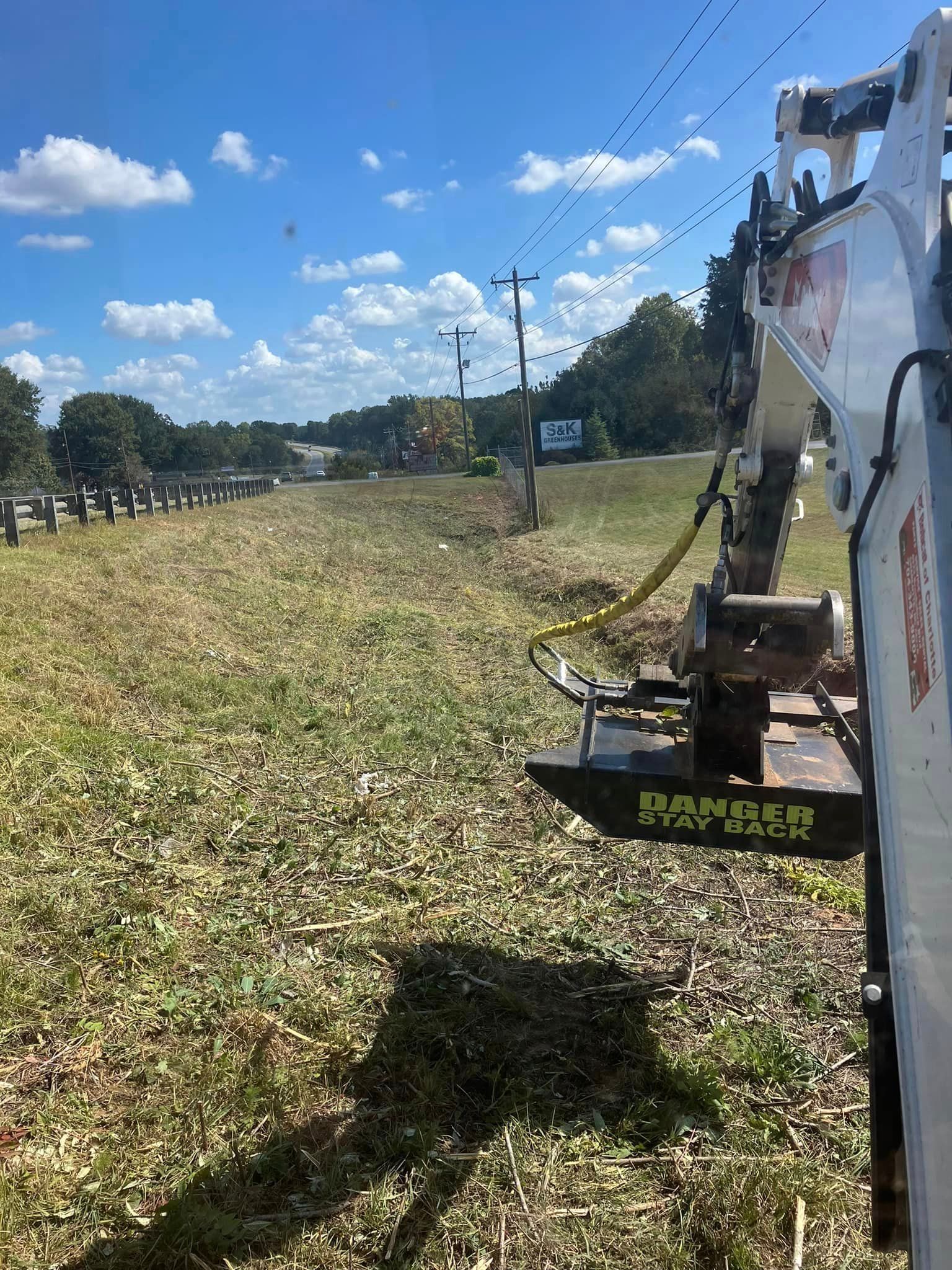 A bulldozer is cutting grass in a field.