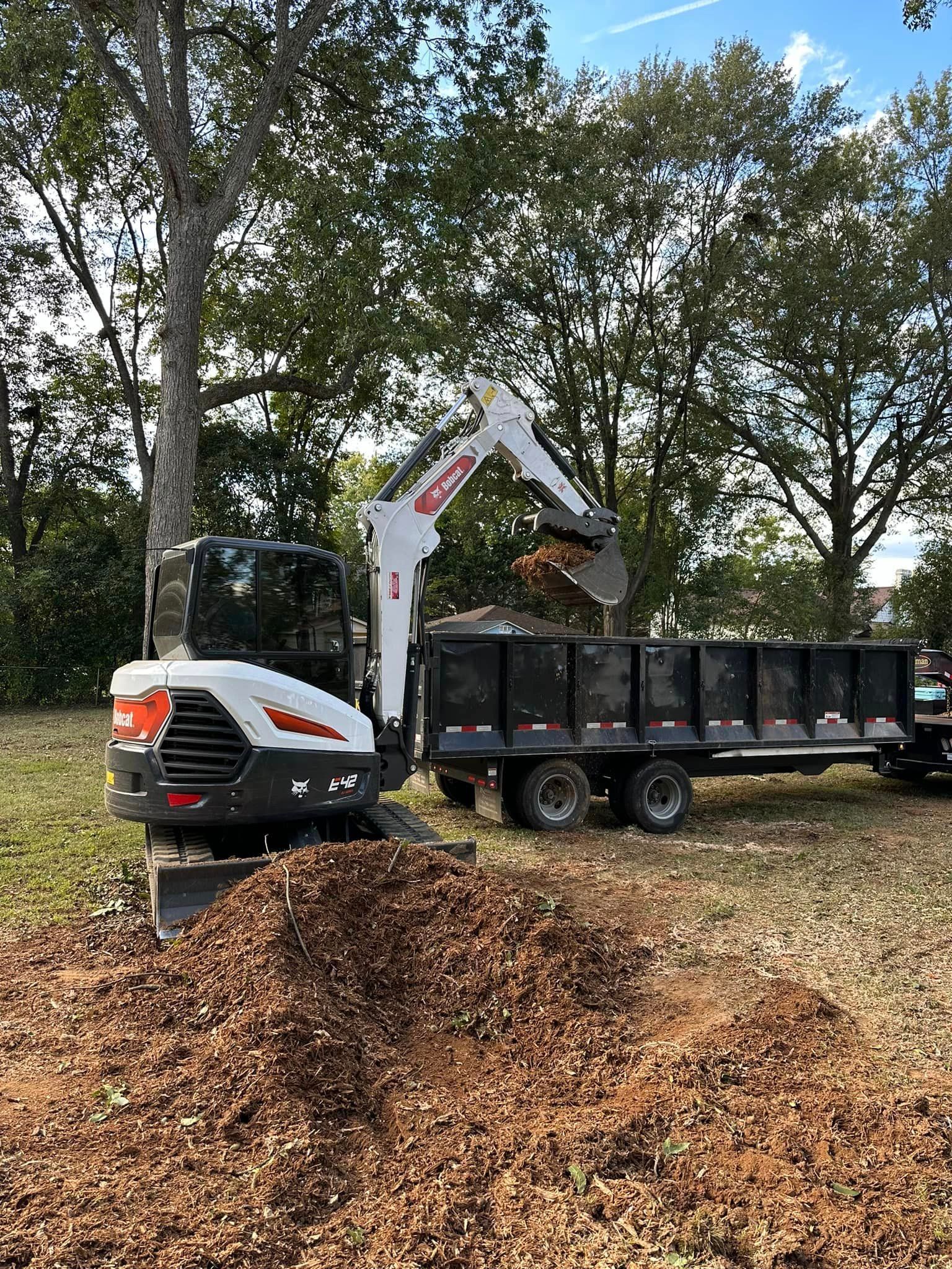 A bulldozer is loading leaves into a dump truck.