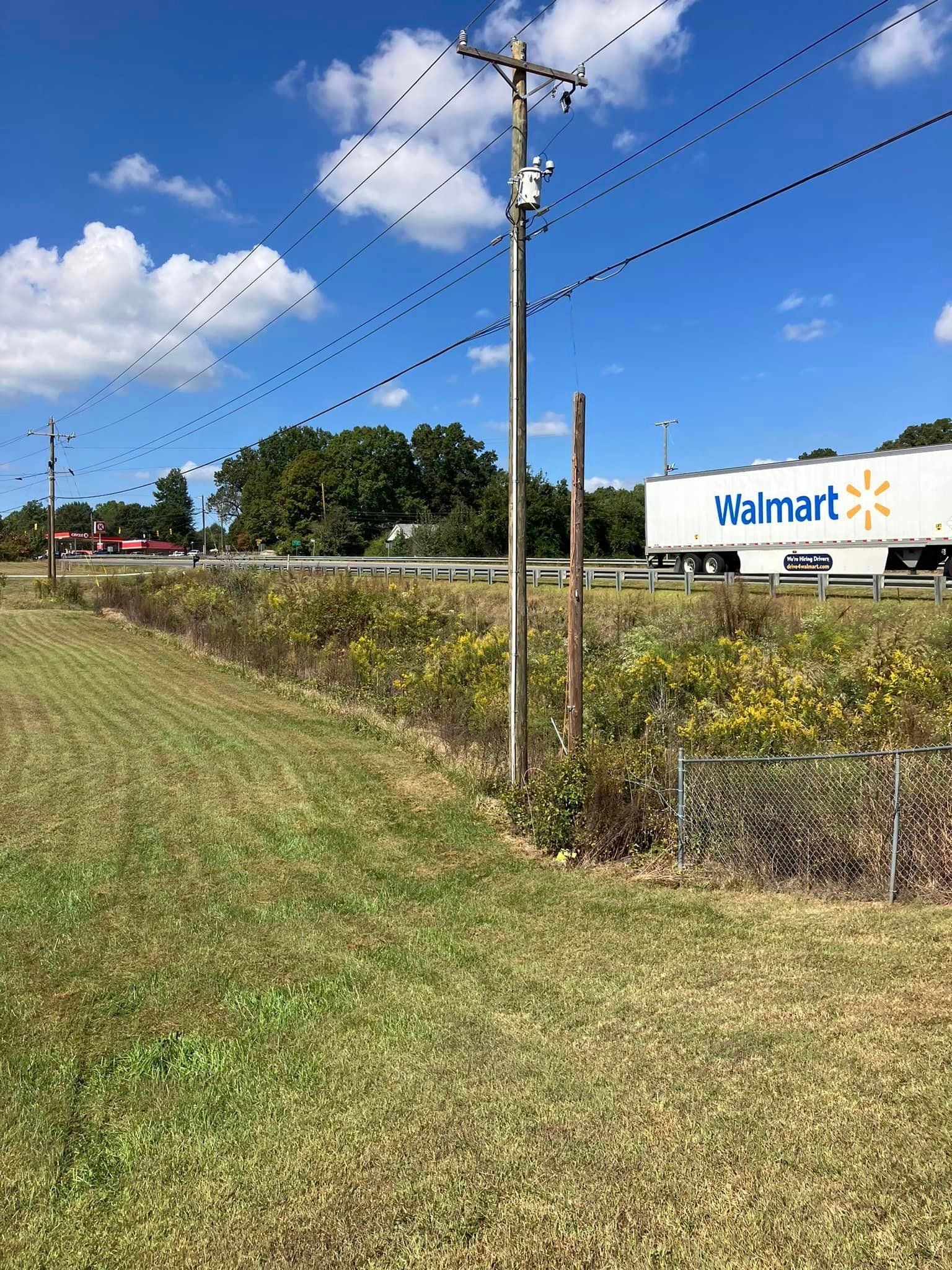 A walmart truck is parked in a grassy field next to a road.