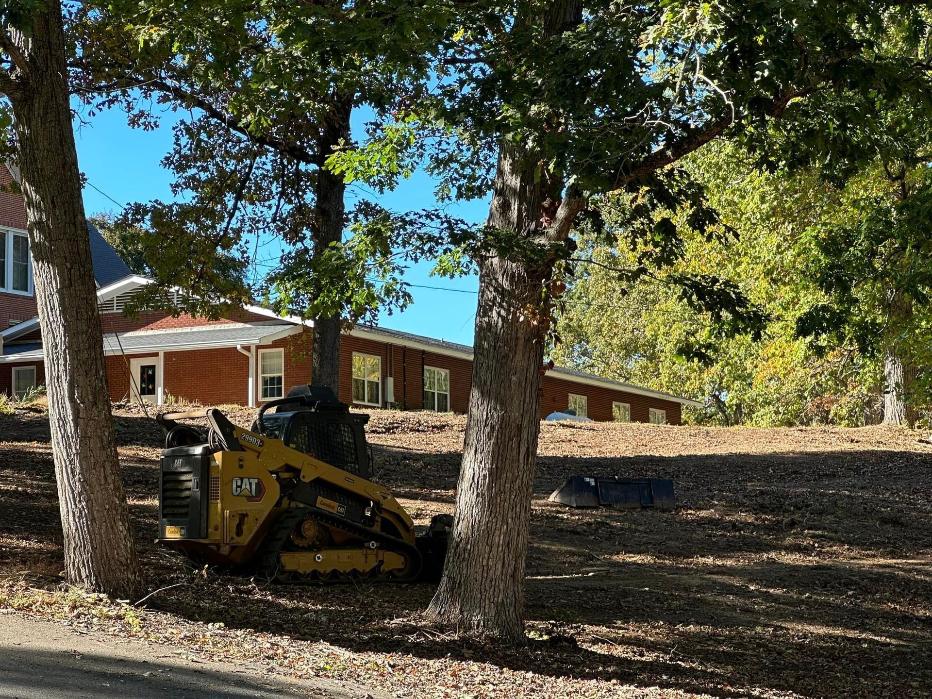 A yellow cat skid steer is parked in front of a house.