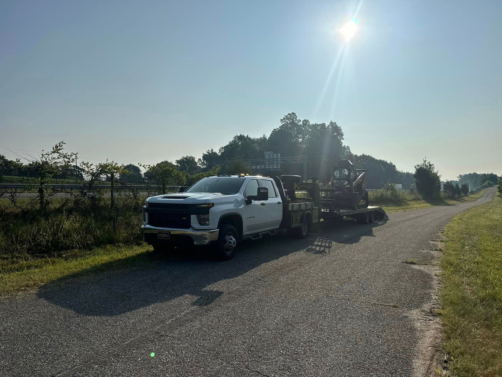 A white tow truck is parked on the side of a gravel road.