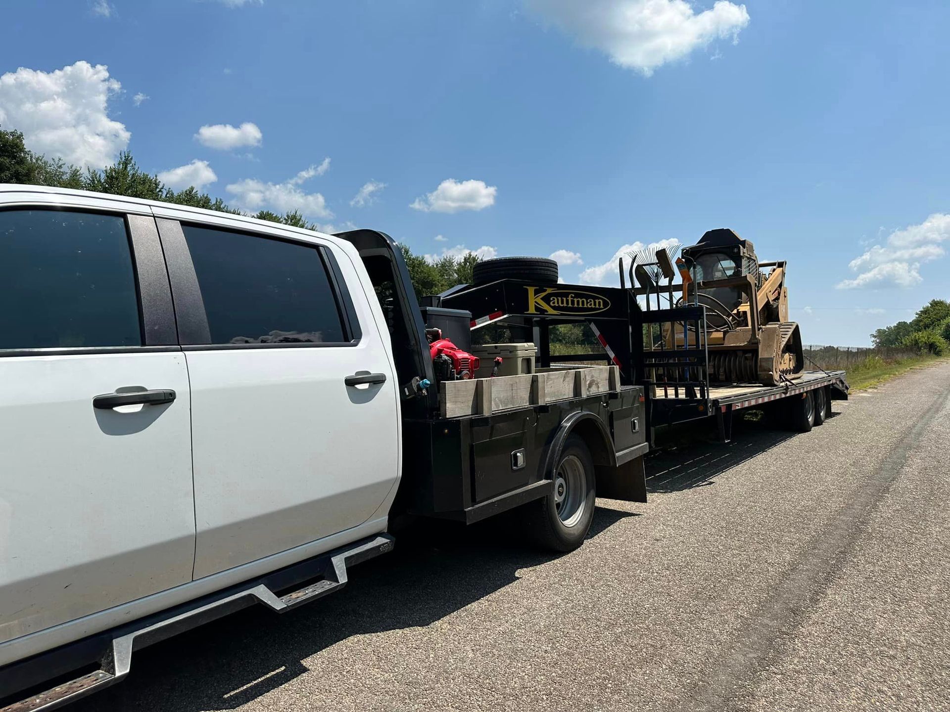 A white truck is towing a trailer with a bulldozer on it.