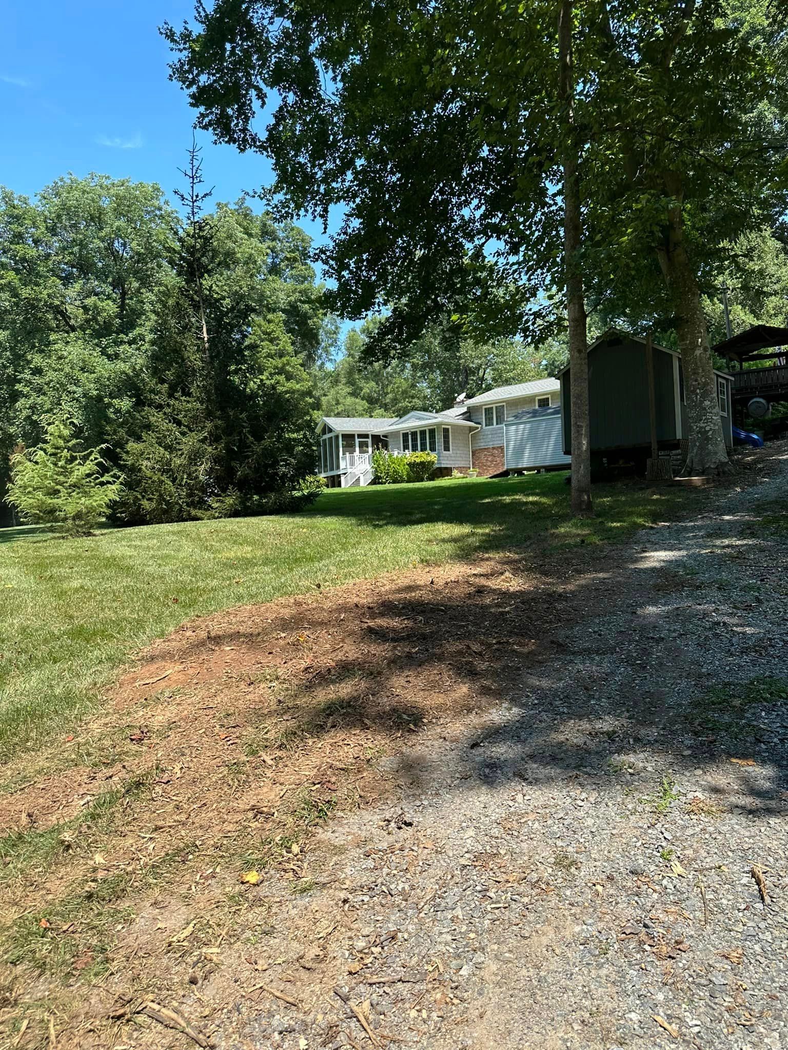 A house is sitting in the middle of a grassy field surrounded by trees.