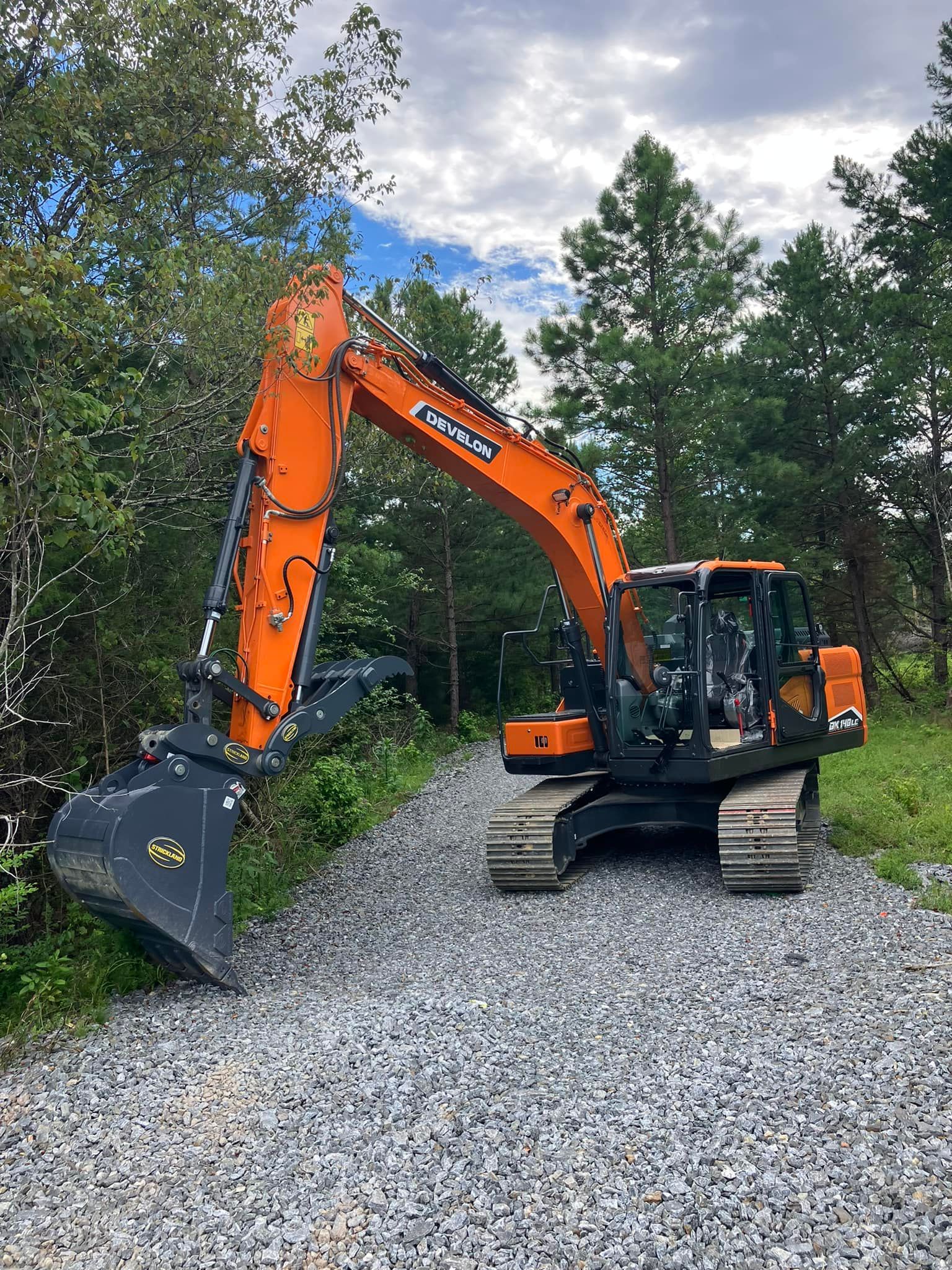 A large orange excavator is sitting on top of a gravel road.