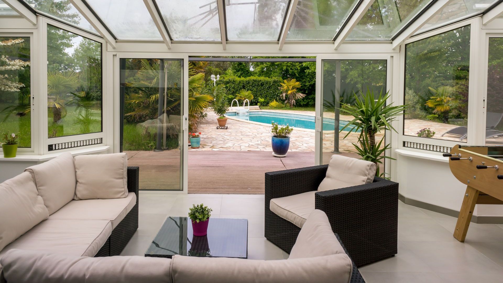 A living room with a couch , chairs , table and a pool in the background.