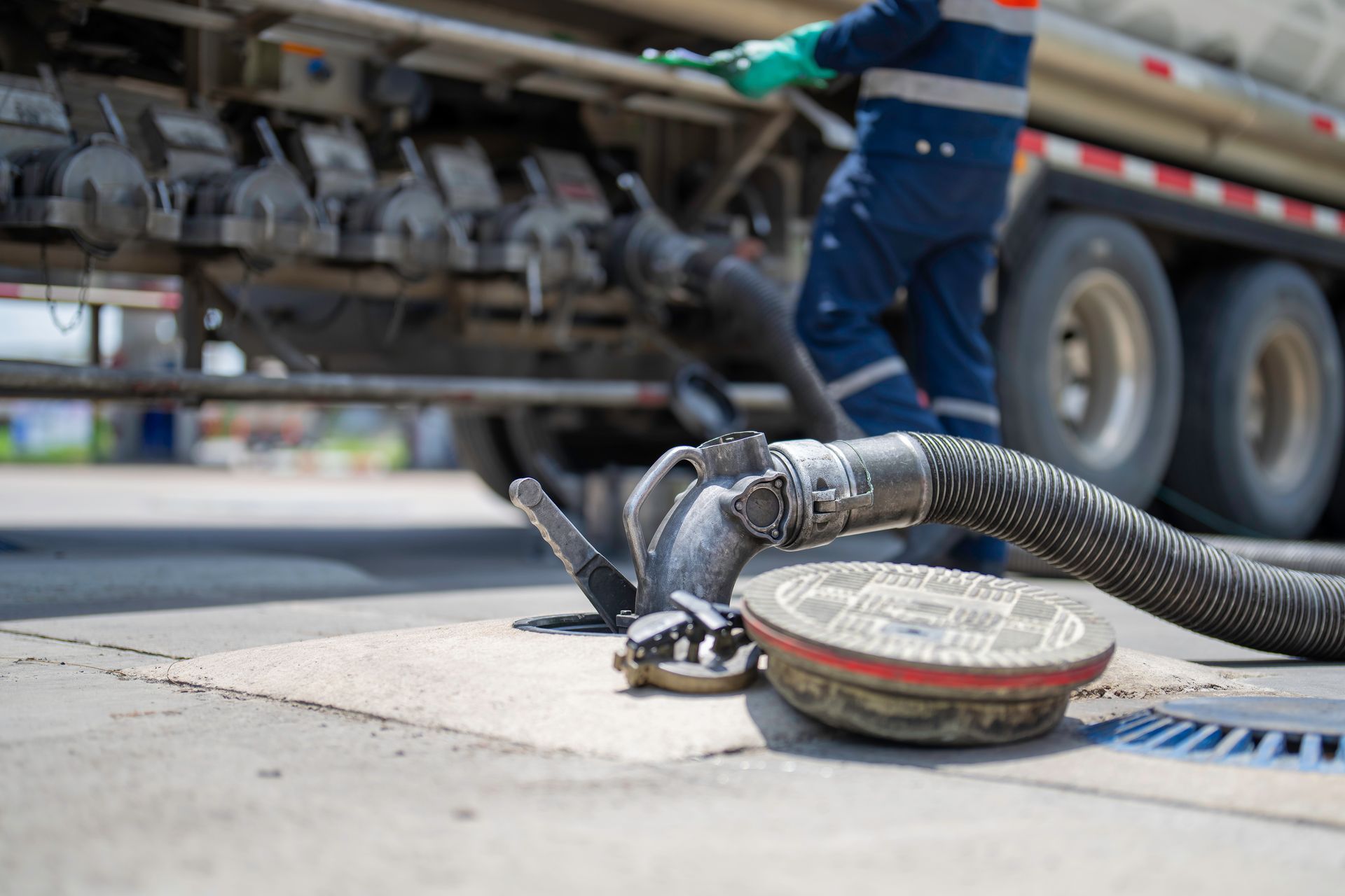 A man is standing next to a truck with a hose attached to it.