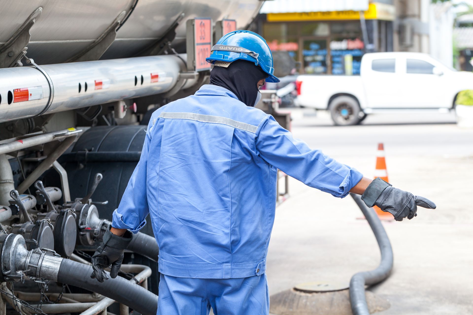 A man in a blue uniform is holding a hose and pointing at something.