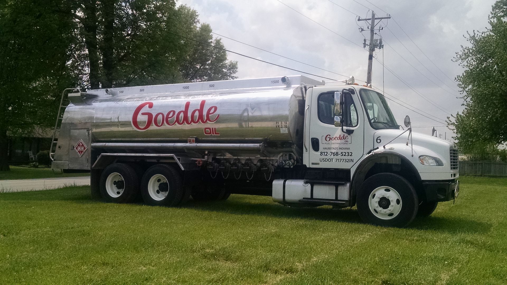 A tanker truck is driving down a road with mountains in the background.