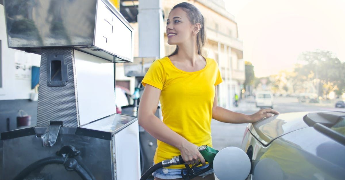 A woman is pumping gas into her car at a gas station.