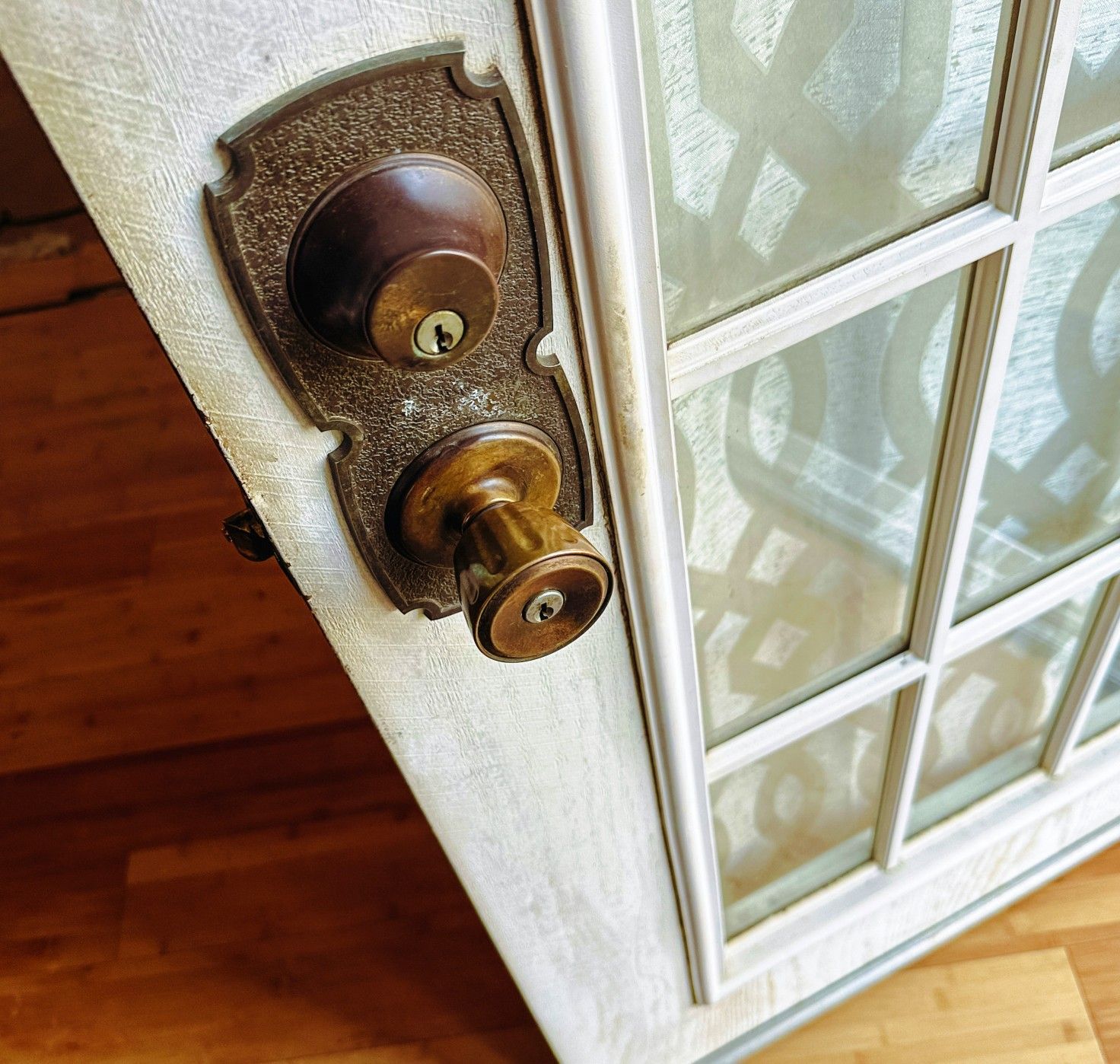 A pale white wooden door with a grid of square glass panels that's ajar.