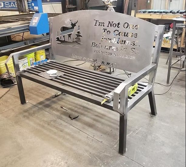 Metal bench with a decorative back; features cutout text 