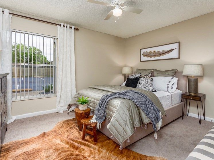 Bedroom with bed, rug, side tables, window, and wall art. Soft colors with warm accents.