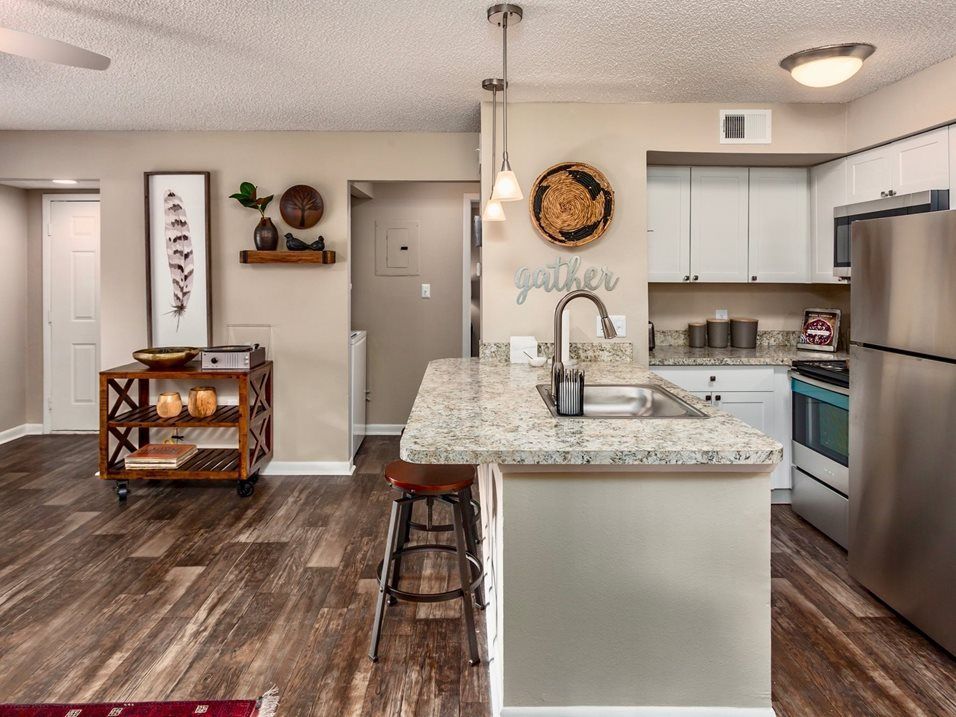 Kitchen with granite island, stainless steel appliances, and wooden flooring.