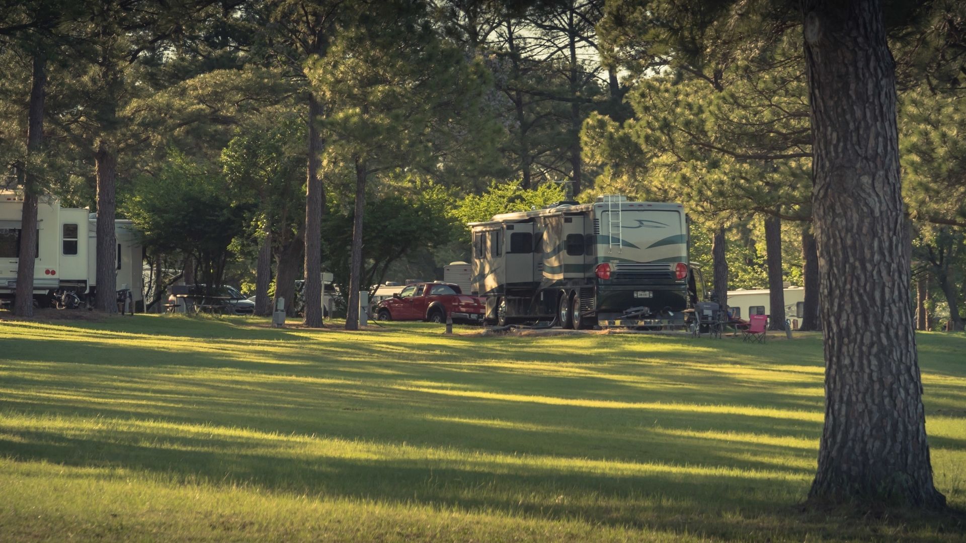 RV campground with grassy areas and trees, sunny day.