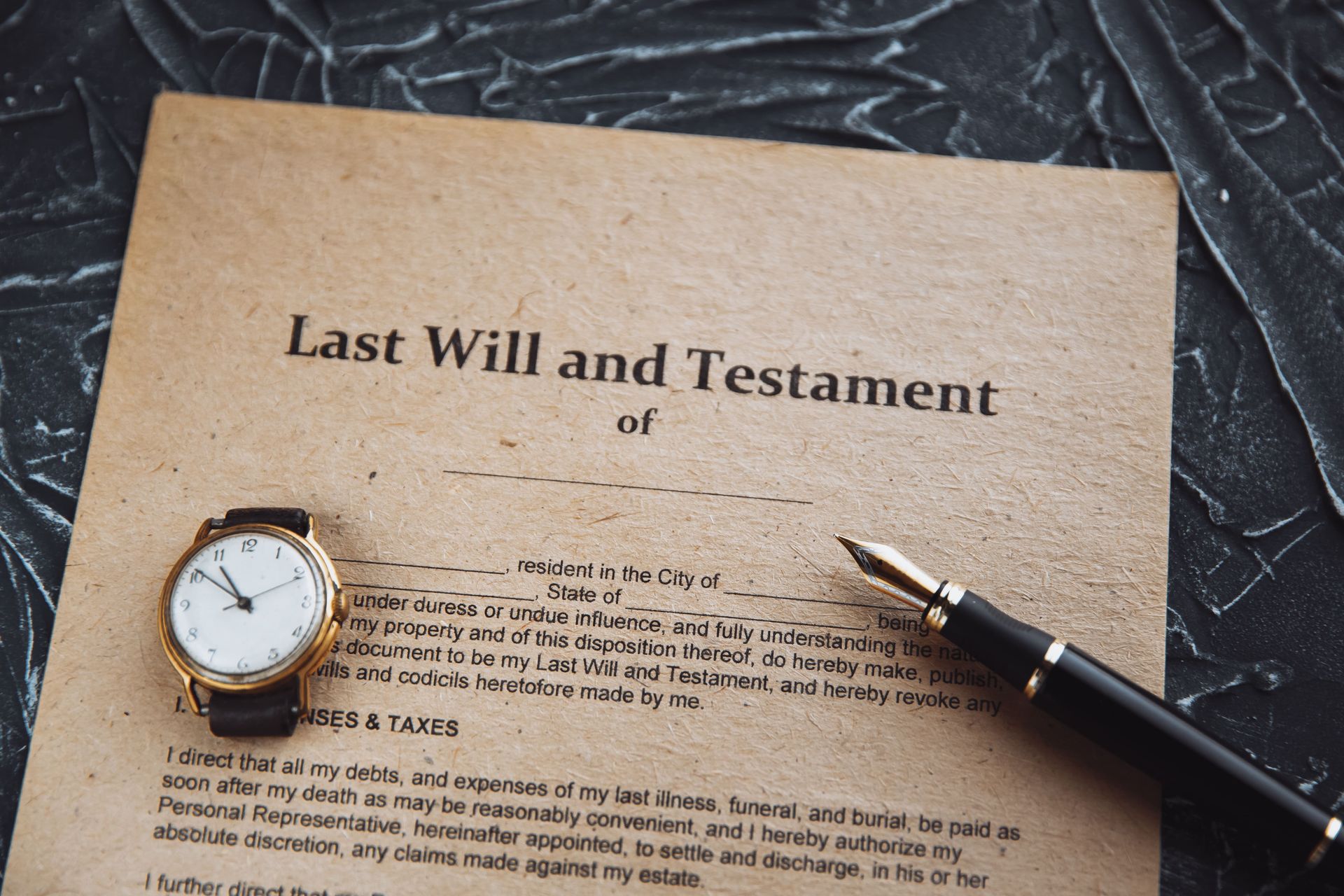 Last Will and Testament document with a pen and wristwatch on a textured surface.