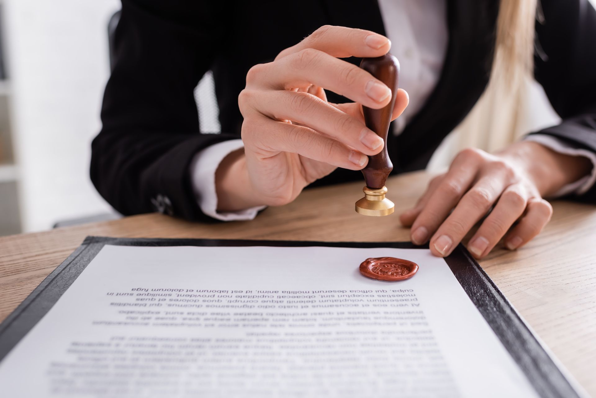 Woman in suit seals document with wax stamp.