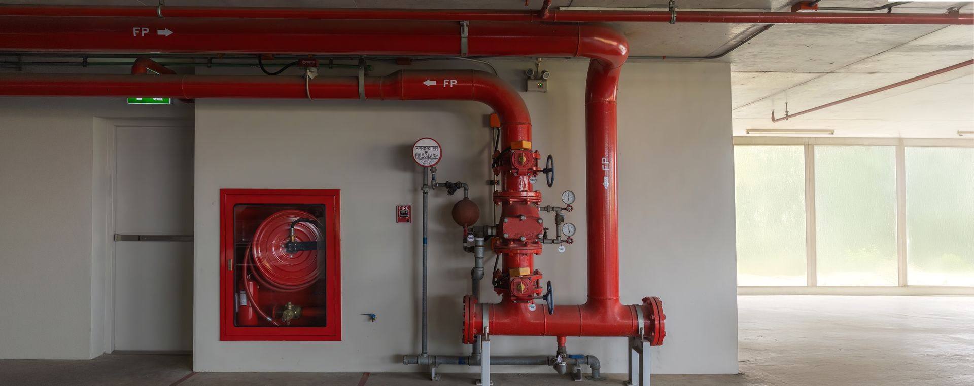Red fire suppression system in a room with a fire hose cabinet.